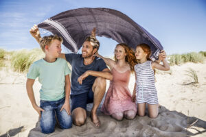 happy family under a blanket on the beach