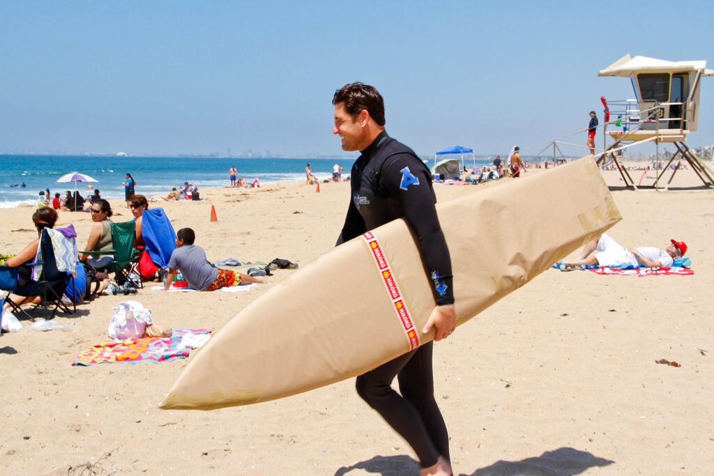 smiling man carrying surfboard on the beach