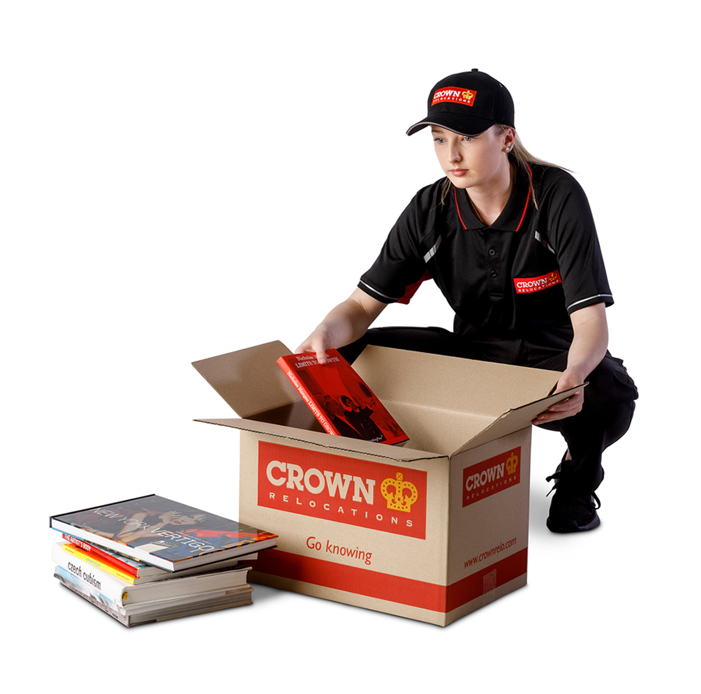 young woman packing the books in cardboard boxes