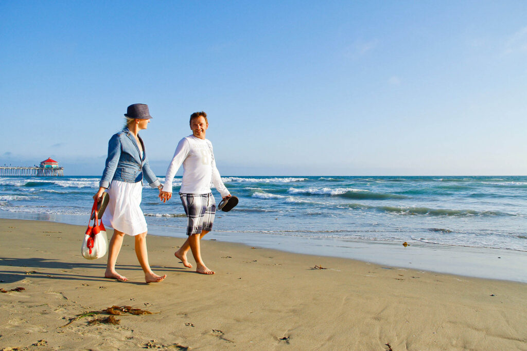 A joyful couple strolling by the beach at sunset, hand in hand