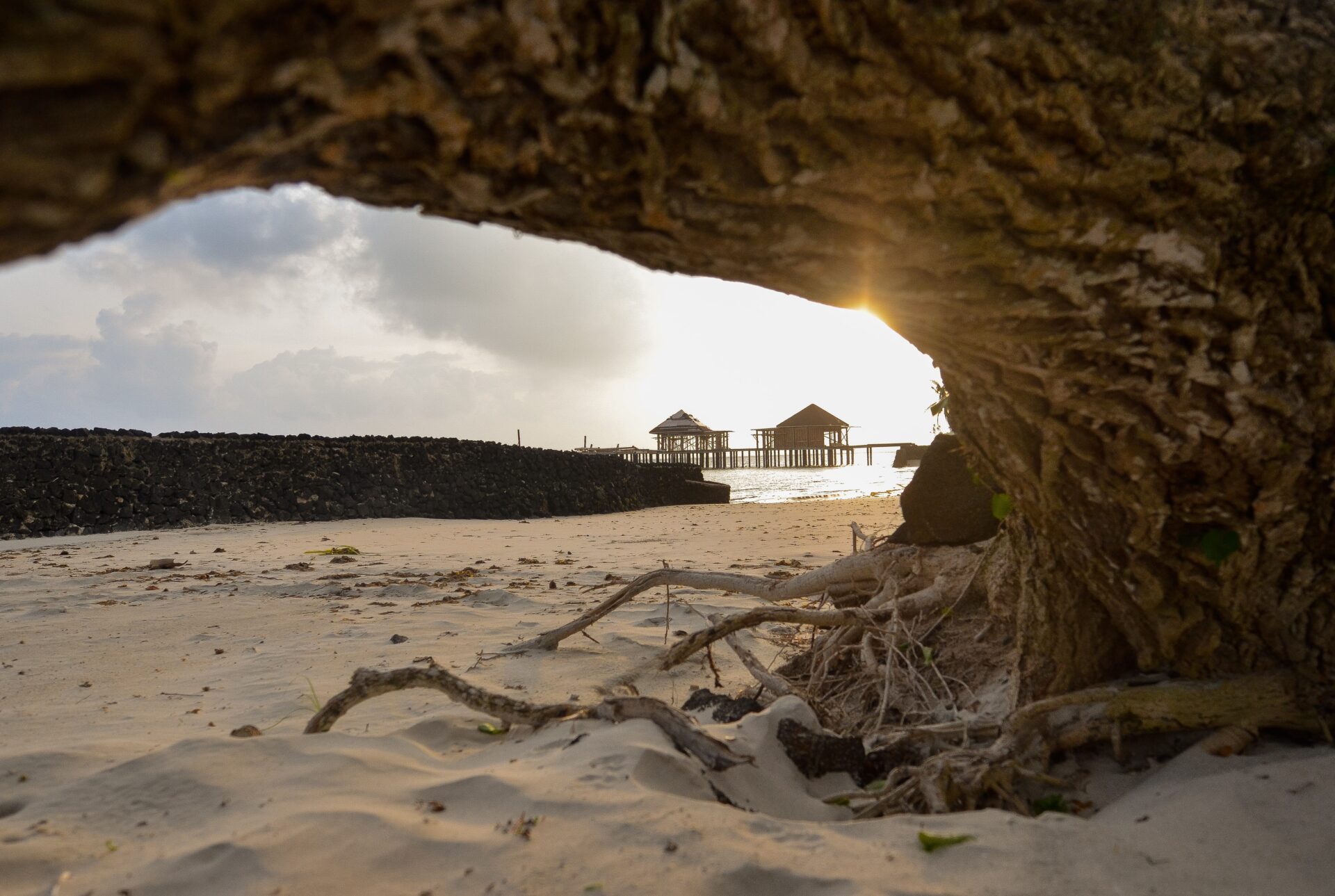 Wooden house on white sand beach under white clouds, daytime in Samoa