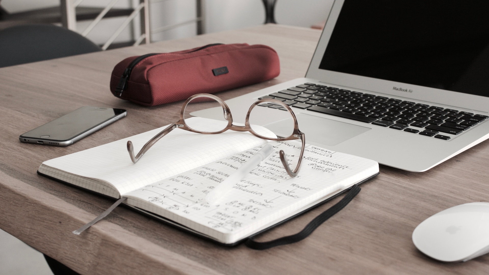 Glasses placed in front of a laptop and notebook