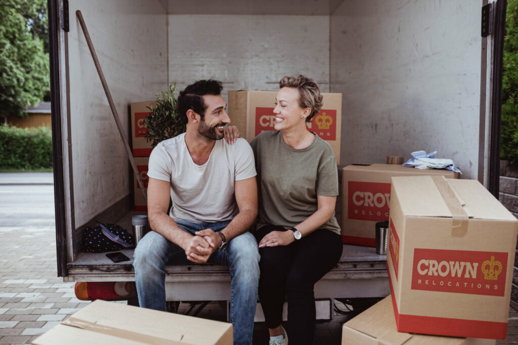Happy couple sitting on truck with Crown Relocations boxes