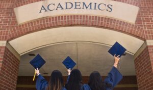 Three women graduates standing in front of the university facade