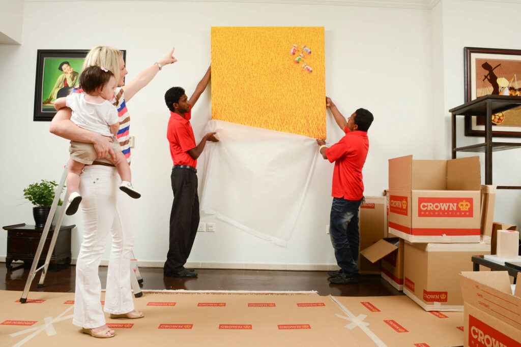 Movers handing a painting on the wall for a customer.